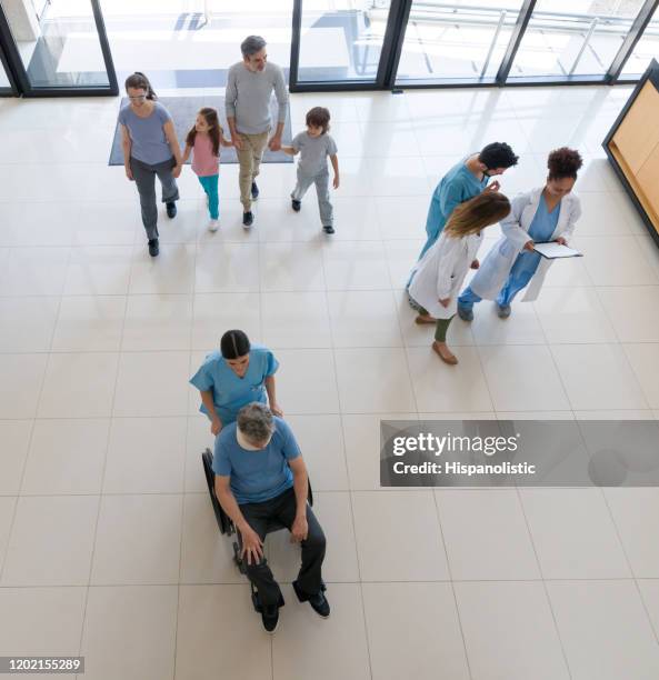 patienten, ärzte und krankenschwestern, die an einem anstrengenden tag in ein und aus einem krankenhaus gehen - krankenhaus eingang stock-fotos und bilder