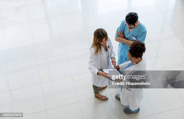 diverse team of doctors and male nurse discussing a case while looking at medical chart on clipboard - healthcare and medicine from above stock pictures, royalty-free photos & images