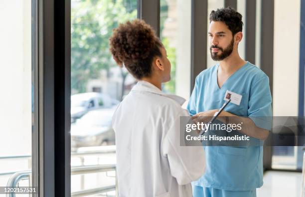 female black doctor and surgeon taking a break talking at the hospital entrance - civilian stock pictures, royalty-free photos & images
