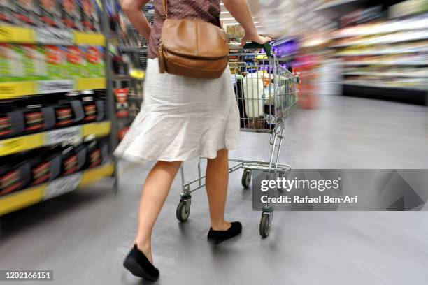 woman in a hurry rushing through supermarket fast during grocery shopping - overloaded shopping cart stock pictures, royalty-free photos & images