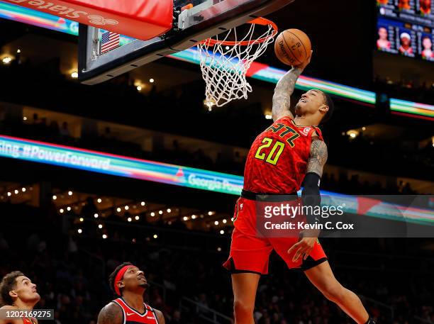 John Collins of the Atlanta Hawks dunks against Bradley Beal of the Washington Wizards in the second half at State Farm Arena on January 26, 2020 in...