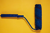Paint brush roller on yellow background. Blue used paint tool as a concept of refurbishing, re branding and changes. Mock-up color object