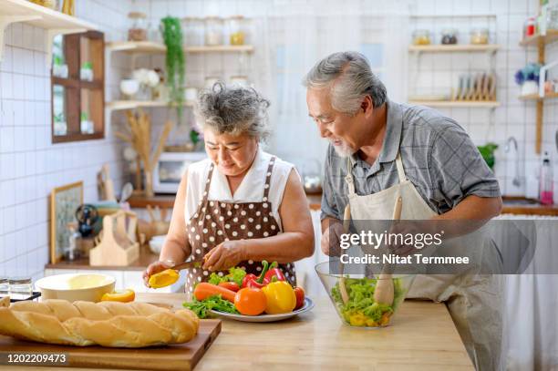 asian elderly happy couple making healthy food in the kitchen at home. elderly spending time together concept. - asian man cooking bildbanksfoton och bilder