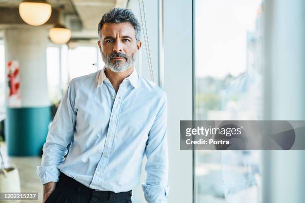 confident mature businessman at coworking space - serious stock pictures, royalty-free photos & images