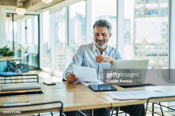 selbstbewusster geschäftsmann, der im coworking space arbeitet - mature reading computer stock-fotos und bilder