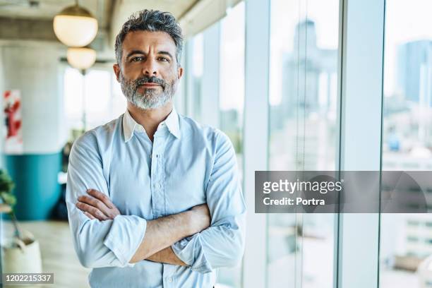 confident businessman with arms crossed in office - shirt stock pictures, royalty-free photos & images