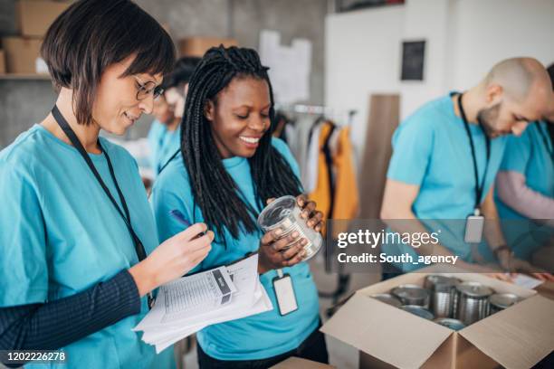 diverse volunteers packing donation boxes in charity food bank - giving tuesday stock pictures, royalty-free photos & images