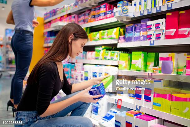 mid adult woman crouching and choosing sanitary pads - tampon stock pictures, royalty-free photos & images