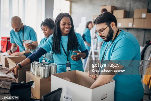 diverse volunteers packing donation boxes in charity food bank - volunteer stock pictures, royalty-free photos & images