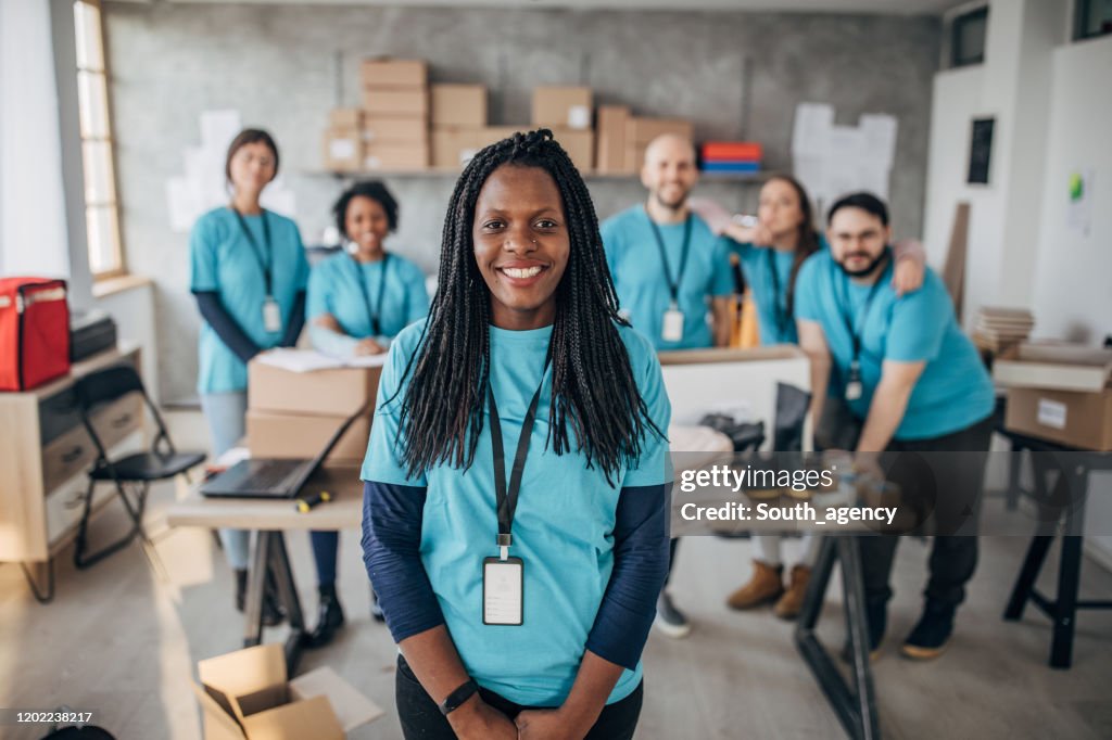 Black woman with volunteers friends in charity food bank