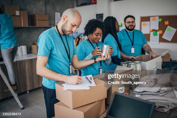 diverse volunteers packing donation boxes in charity food bank - packing food stock pictures, royalty-free photos & images