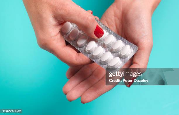 woman opening blister pack of pills - ibuprofen stock pictures, royalty-free photos & images