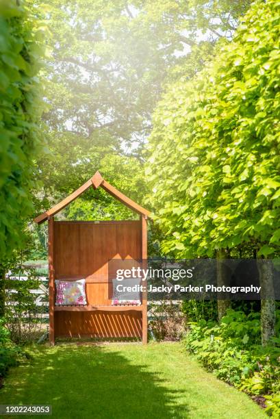 a wooden covered garden bench arbour in a sunny english garden in the summer - hornbeam stockfoto's en -beelden