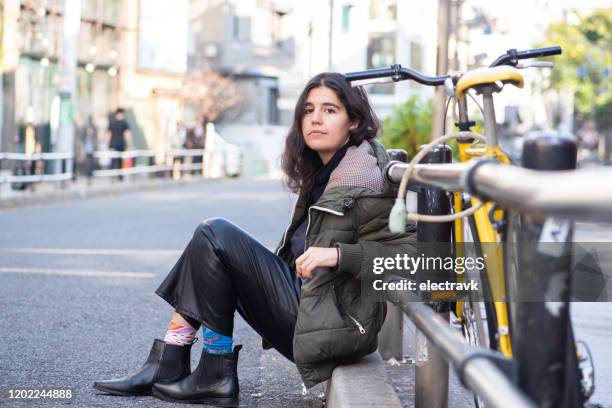 joven sentada junto a su bicicleta - mismatch fotografías e imágenes de stock