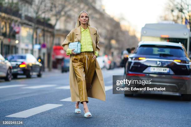 Leonie Hanne wears earrings, a pistachio-green quilted shirt, a beige coat, a Bottega Veneta light blue quilted clutch, light brown leather wide-legs...