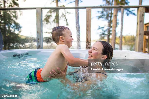 young boy splashing and playing with mother in swimming pool - girls in hot tub fotografías e imágenes de stock