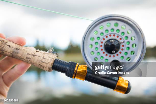 fisherman holding fly fishing rod. - fishing reel foto e immagini stock