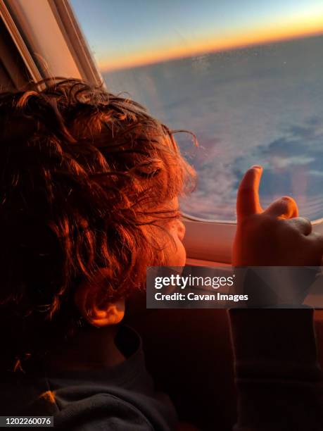 little boy looking out of a plane window at the sunrise - zagreb night stock pictures, royalty-free photos & images