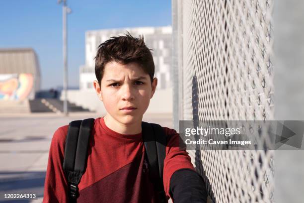 portrait of cheerful teen leaning on metallic fence, looking camera - spain teen face bildbanksfoton och bilder