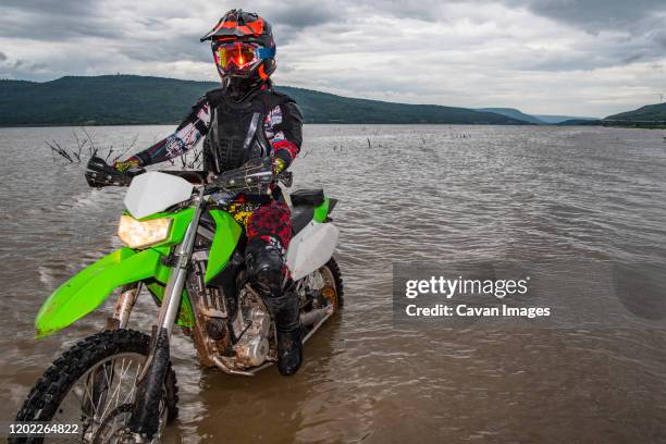 woman standing with her dirt bike in a lake - google ventures stock pictures, royalty-free photos & images