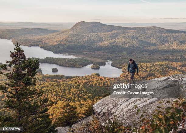 male hiker walks along cliff with view on appalachian trail, maine - appalachian trail stock pictures, royalty-free photos & images