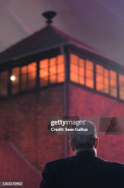 Man wearing a yarmulka stands next to the main tower at the entrance to the former Auschwitz-Birkenau concentration camp, which is covered under a...