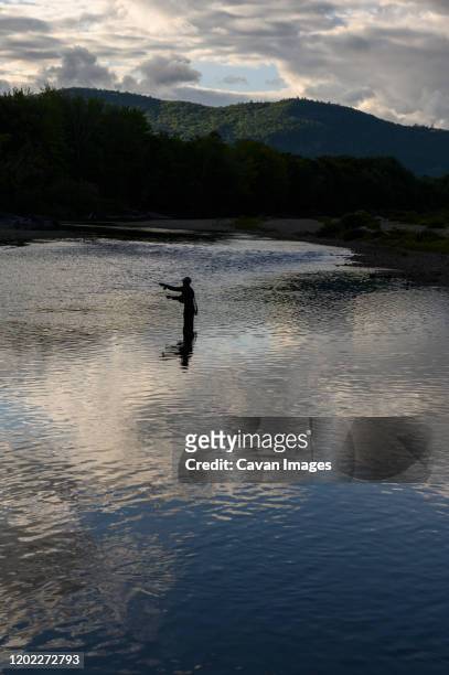 a fly fisherman casting on a river in the evening. - lake solitude (new hampshire) fotografías e imágenes de stock