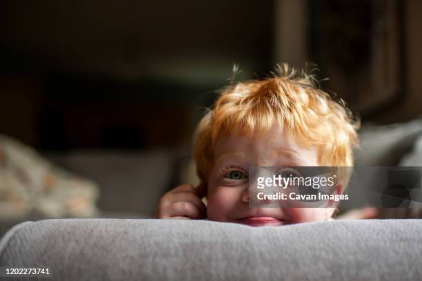 up close of toddler boy with silly expression laying on couch at home - funny baby faces stock pictures, royalty-free photos & images