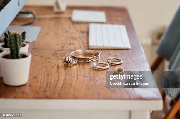 woman's silver jewellery on a desk next to a computer - silver ring stock pictures, royalty-free photos & images