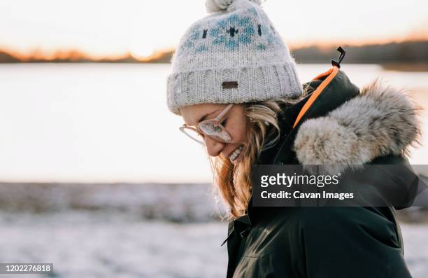 portrait of woman with snow in her hair smiling at sunset in winter - bonnet noel stock pictures, royalty-free photos & images