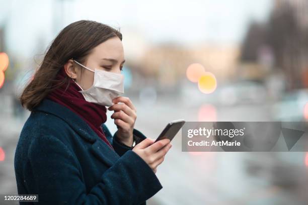 young girl wearing a protective face mask and checking air pollution with smartphone - weather alert stock pictures, royalty-free photos & images