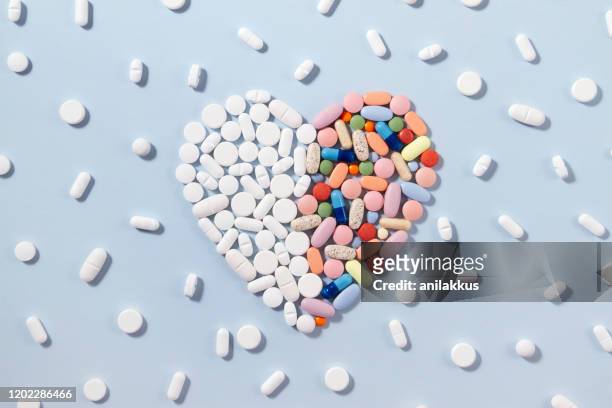 青い背景にハート型の白と色の丸薬 - heart pill ストックフォトと画像