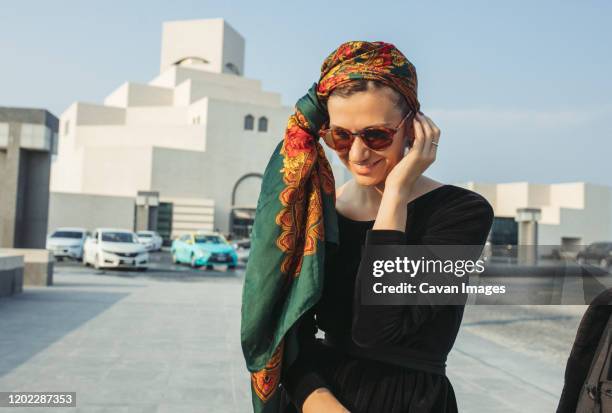 young woman with headwrap smiling and looking down - doha people stock pictures, royalty-free photos & images