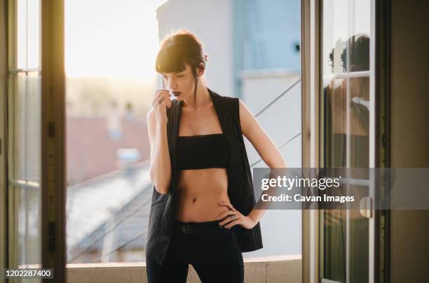 a girl standind on a balcony of her flat. - flat stomach stock-fotos und bilder