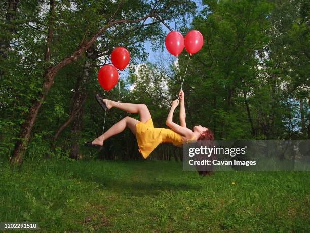 adorable young brunette girl levitating on balloons in a park - helium stock pictures, royalty-free photos & images