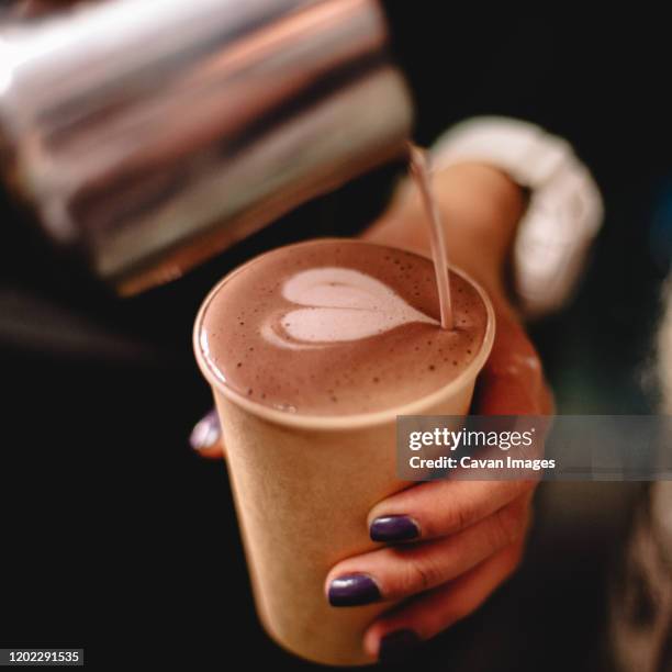 female barista pouring milk in coffee making heart shape - take away coffee cup stock pictures, royalty-free photos & images