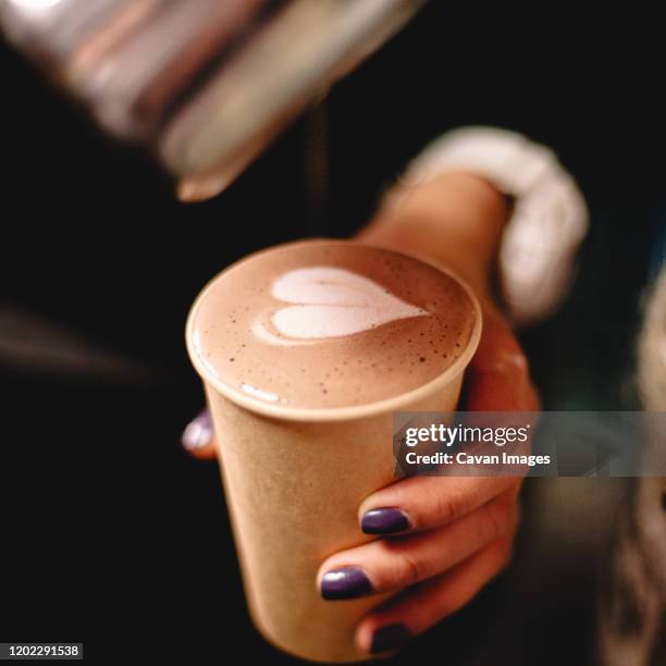 female barista holding disposable cup of coffee with heart shape - takeaway coffee cup stock pictures, royalty-free photos & images