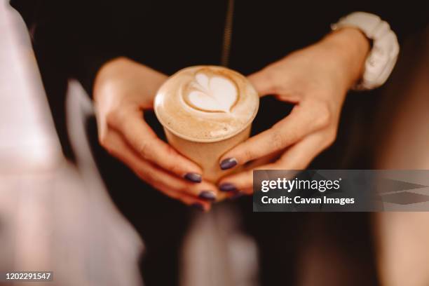 cropped image of female hands holding disposable cup of coffee - takeaway coffee stockfoto's en -beelden