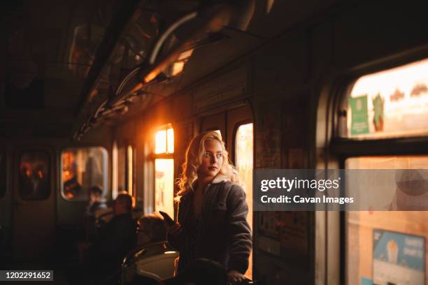 young woman looking through window traveling in subway train - house golden hour stock pictures, royalty-free photos & images