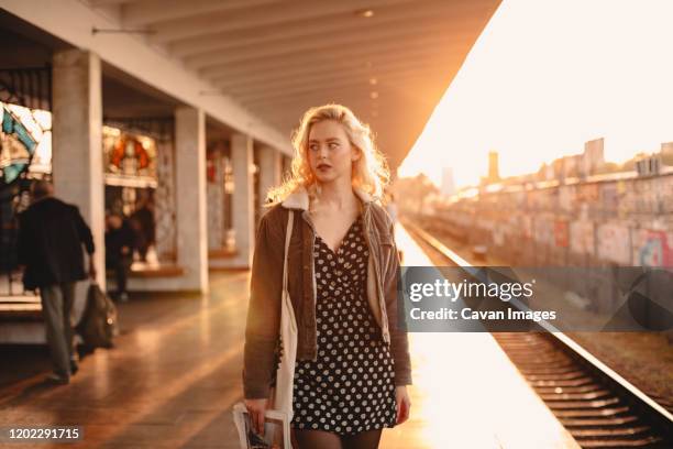 young woman waiting for train at subway station at sunset - plataformas de formação imagens e fotografias de stock