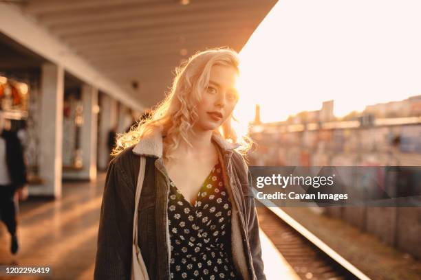 young woman waiting for train at subway station at sunset - goldene stunde stock-fotos und bilder