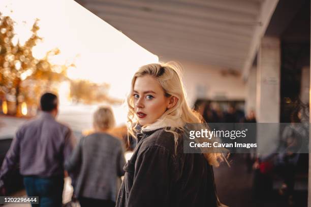 teenage girl looking back at camera walking on subway station - woman lipstick rearview stock-fotos und bilder