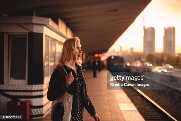 thoughtful young woman waiting for train at subway station at sunset - femme métro photos et images de collection