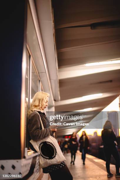 young woman using smart phone waiting for train at subway station - waiting for train stock pictures, royalty-free photos & images