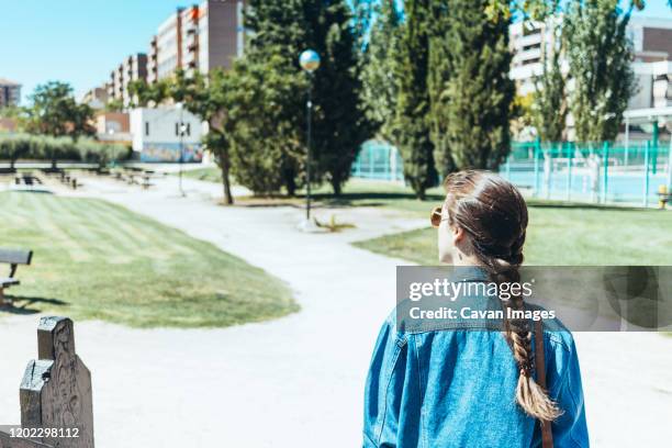 young woman seen from behind walking through a park - september 12 stock pictures, royalty-free photos & images