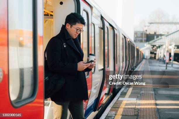 businessman using smart phone on the train platform - phone street style stock pictures, royalty-free photos & images