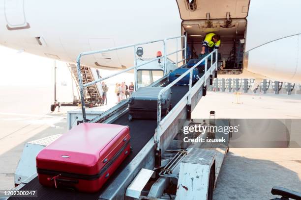 airport service crew loading luggage to the airplane - conveyor belt stock pictures, royalty-free photos & images