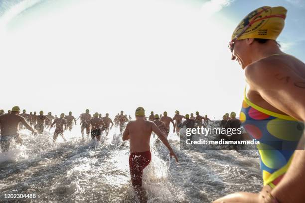 eine schwimmer-menge läuft ans wasser, nachdem ein freiwasser-wettbewerb gestartet war - triathlet stock-fotos und bilder