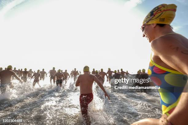 a swimmers crowd running to the water after a open water competition had start - triathlon swim stock pictures, royalty-free photos & images