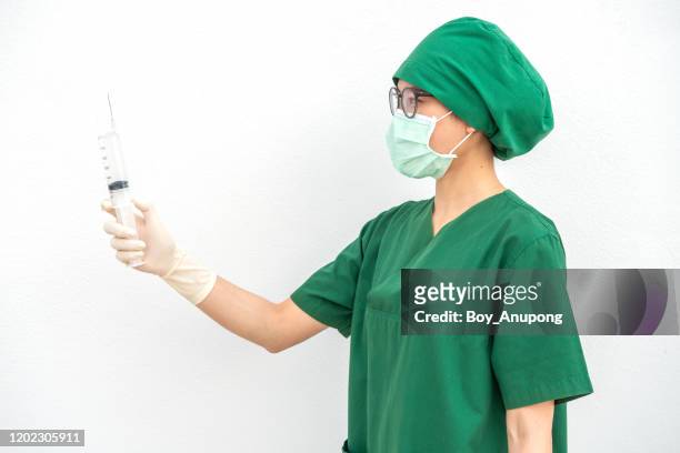 portrait of young surgery nurse/doctor holding a syringe needle and preparation for injection. - surgeon holding needle stock-fotos und bilder